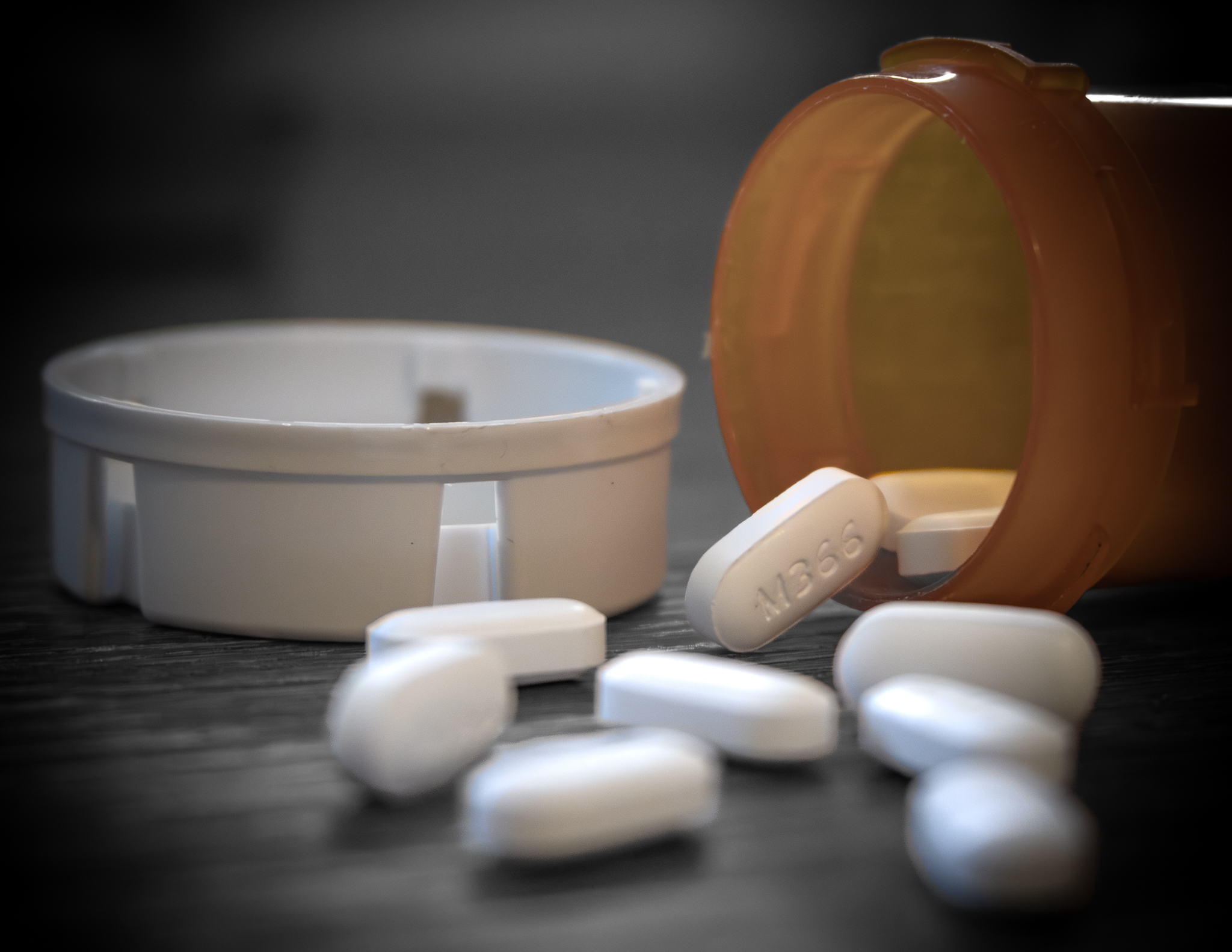 Prescription pills spilling from an open medication bottle