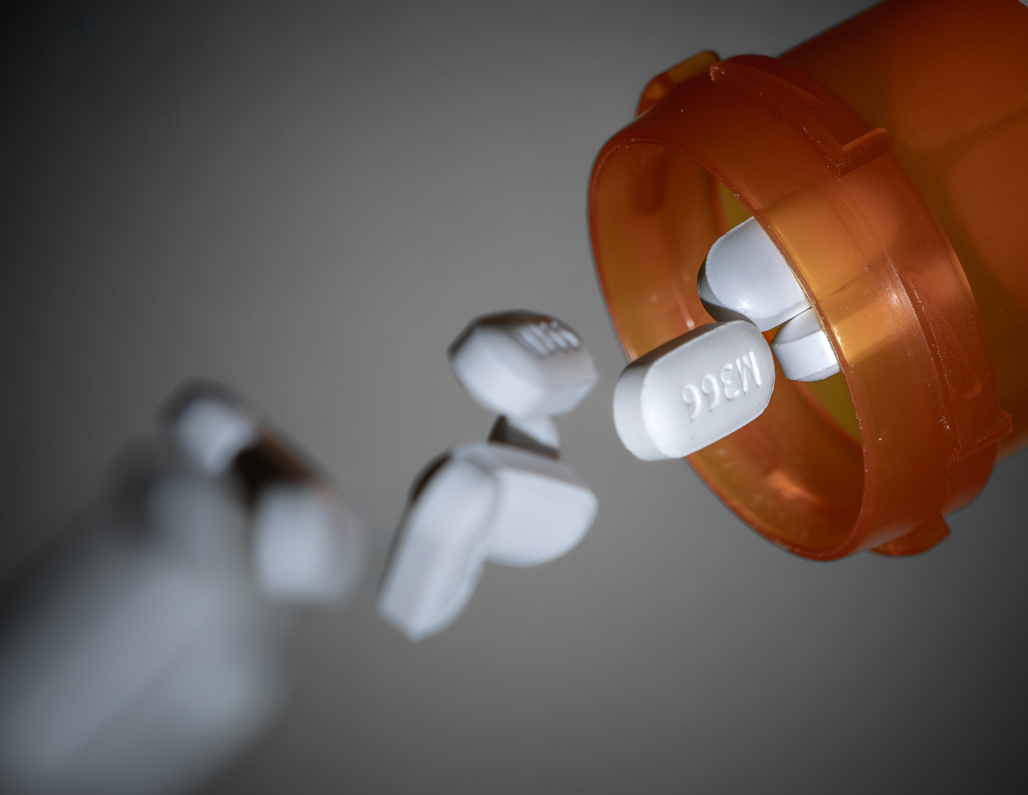Prescription medication spilling from an open orange bottle.