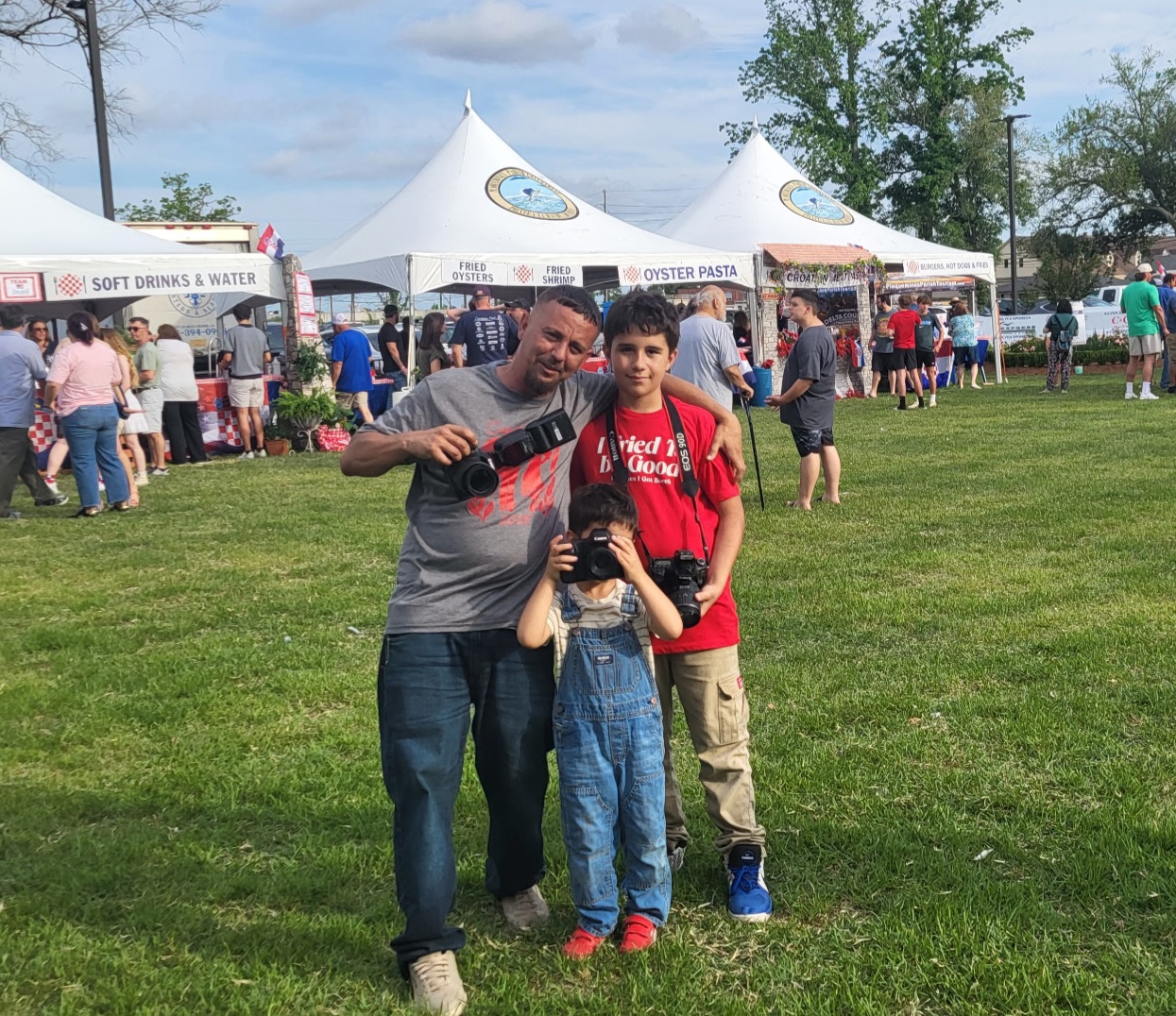 Tracy Newby and his two sons holding cameras while working at a Louisiana festival