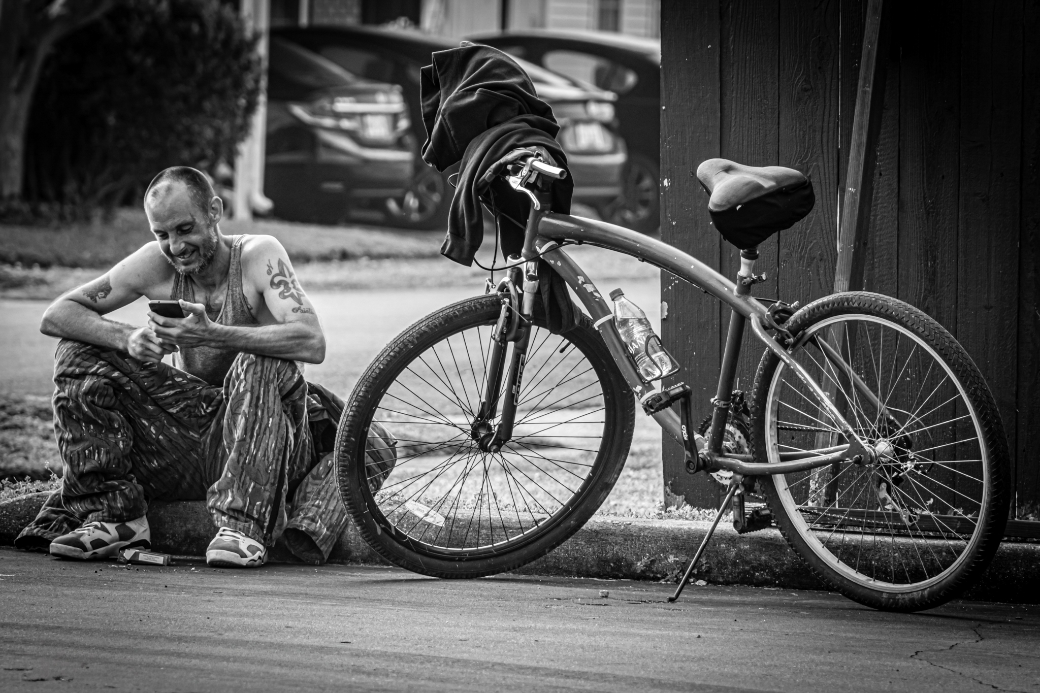 A man sitting beside a bicycle on a city street.